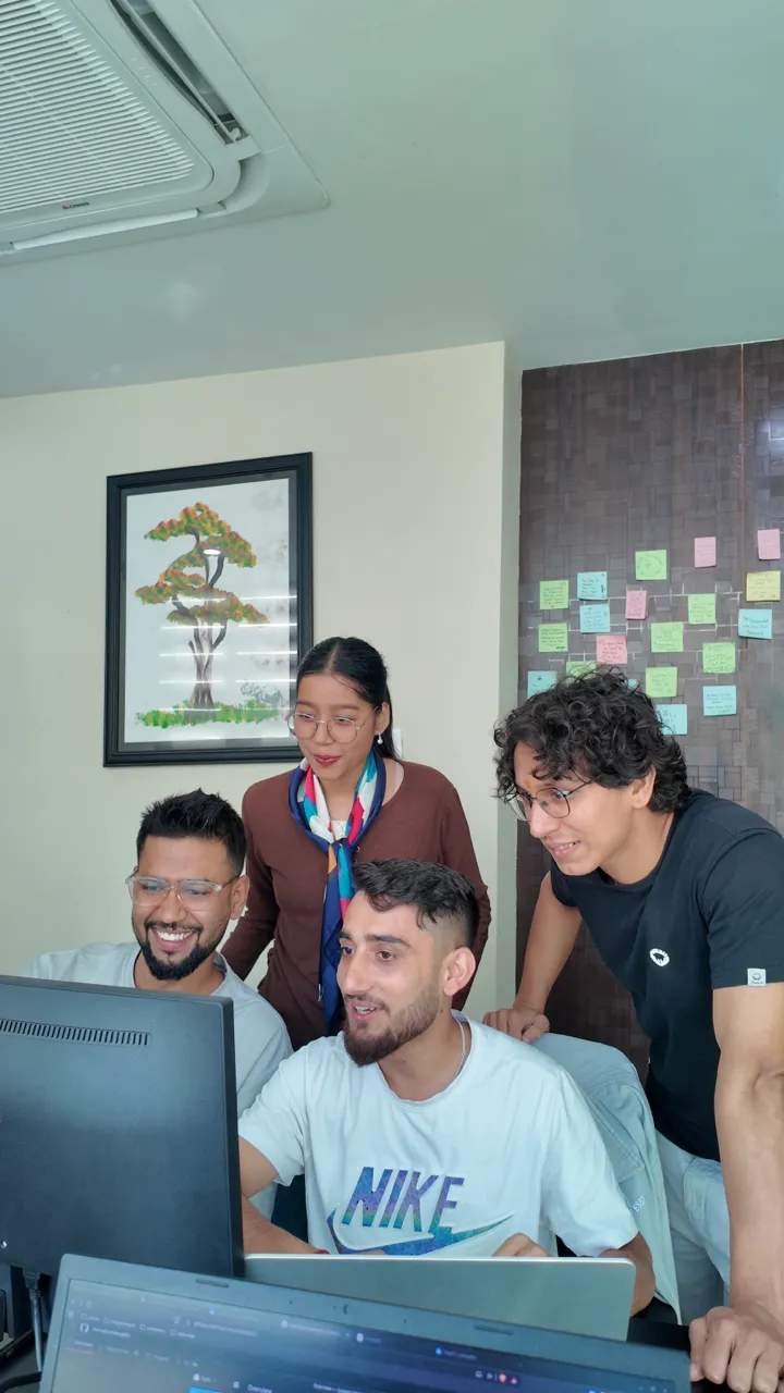 NepalHRM team gathered around a monitor beside the sprint planning board in the Kathmandu office